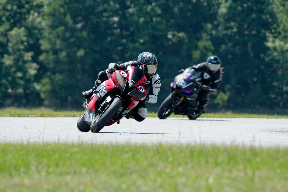 Two motorcycle riders leaning through a turn together on a racetrack